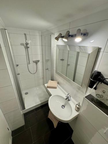 a white bathroom with a sink and a shower at Haus Edeltrud - Ferienwohnung Moselufer in Bernkastel-Kues