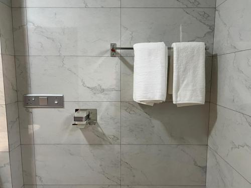 a bathroom with white marble walls and towels at Sol & Luna in Katunayaka