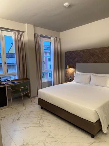 a bedroom with a bed and a desk and windows at Baires Guest House 2 in Milan