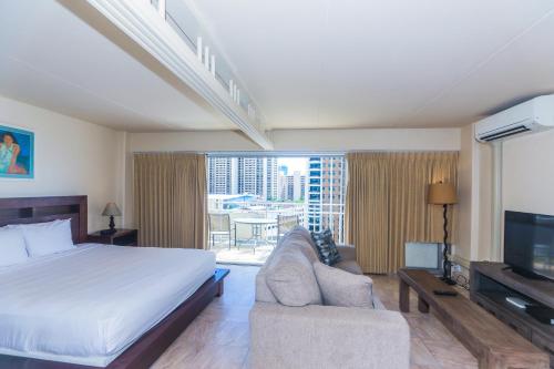 a bedroom with a bed and a television and a couch at Ilikai Tower 936 in Honolulu
