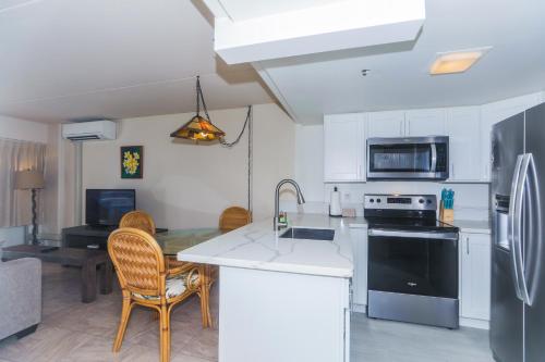 a kitchen with white cabinets and a table with chairs at Ilikai Tower 936 in Honolulu