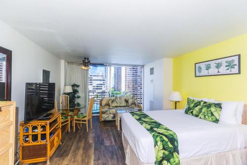 a bedroom with a bed and a desk and a tv at Ilikai Marina 1285 in Honolulu