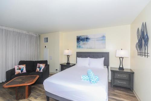 a bedroom with a white bed and a couch at Ilikai Marina 1381 in Honolulu