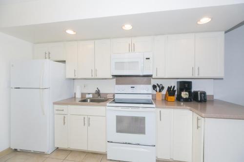 a kitchen with white cabinets and white appliances at Ilikai Marina 1781 in Honolulu