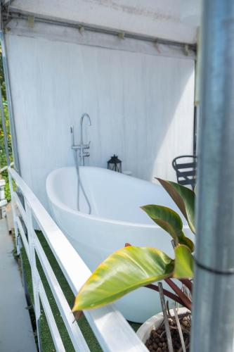 a white bath tub in a bathroom with a plant at ลักษณ์ภูชี้ฟ้า 2 แบบโดม in Ban Seng Choi