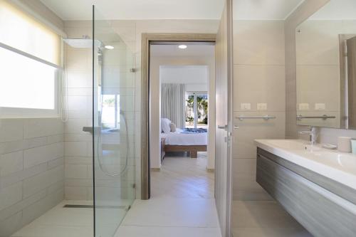 a bathroom with a glass shower and a sink at Destination Jelly Playa Coral Condo in Punta Cana