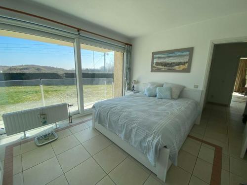 a bedroom with a large bed and a large window at SunnySide-of-TheSea - stunning view on nature, big terraces all around - 150 m from sea, beach, stores, restaurants & beach bars - with parking in Nieuwpoort