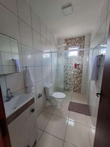 a white bathroom with a toilet and a sink at Calma e tranquilidade em Barra Velha in Barra Velha