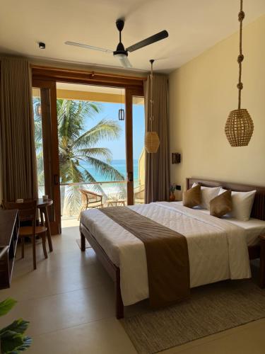 a bedroom with a large bed and a large window at Piña Boutique Hotel - Beachfront in Habaraduwa Central