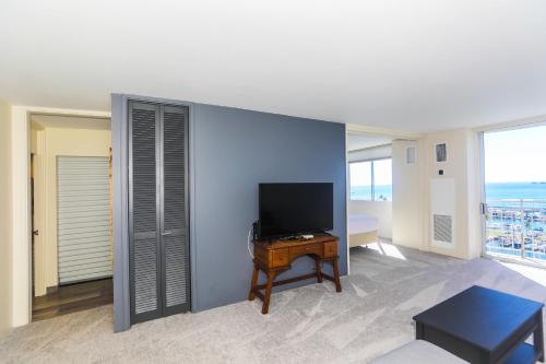 a living room with a tv on a wall with a table at Ilikai Marina 1386 in Honolulu