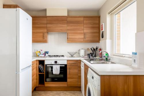 a kitchen with wooden cabinets and a white refrigerator at About Tern - 10-Minute Walk to Poole Quay, with Harbour Views in Poole