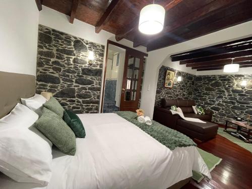 a bedroom with a large bed and a stone wall at Casa Gouveia in Ribeira Brava