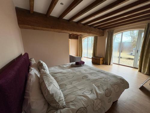 a bedroom with a large bed with a large window at The Granary, Wolds Way Holiday Cottages, spacious 3 bed cottage in Cottingham