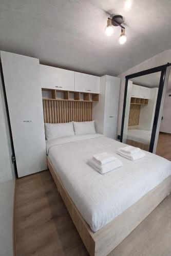 ein Schlafzimmer mit einem großen weißen Bett, auf dem zwei Handtücher liegen in der Unterkunft Tiny House Doi Frați in Drăguş