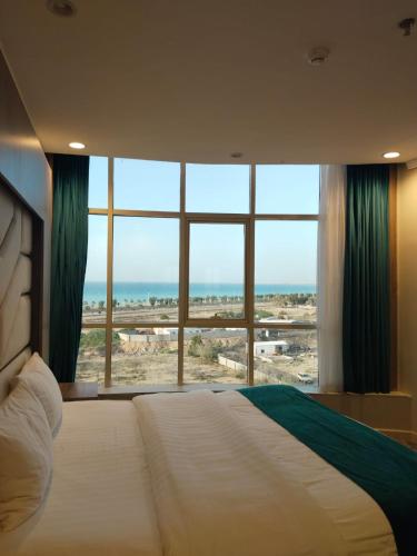 a bedroom with a large bed and a large window at همم للشقق المخدومة أملج-HMM Appartment Service in Umm Lajj