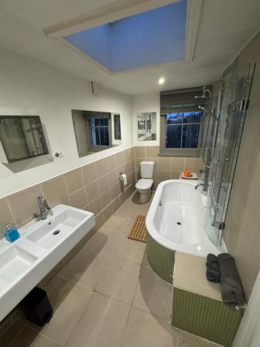 a bathroom with a tub and a sink and a toilet at Griffin House Holiday Apartments in London