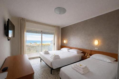a hotel room with two beds and a window at Hotel ABA FRONTE MARE in Milano Marittima