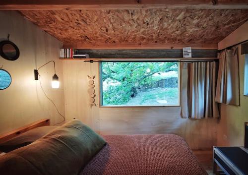 a bedroom with a window in a tiny house at Lodge La Clède in Concoules