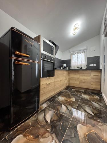 a kitchen with a black refrigerator and wooden cabinets at L'instant étoilé in Châteauneuf-lès-Martigues