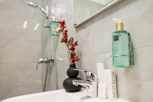 a bathroom sink with a bottle of soap and a vase with flowers at Le Blanc ApartHotel in Bucharest