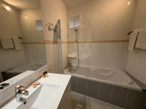 a bathroom with a tub and a sink and a shower at The Originals Boutique, Le Grand Hôtel Molière, Pézenas in Pézenas