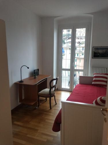 a bedroom with a desk and a bed with a red bedspread at I ciottoli di Bogliasco in Bogliasco