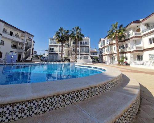 a swimming pool in front of some apartment buildings at Caballito del Mar apartment in Punta Prima