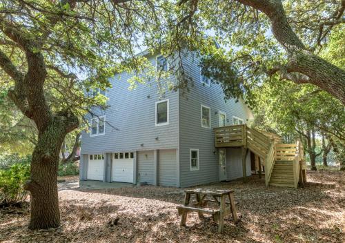 a house with a tree and a wooden bench at Casa La Playa - Duck, Sanderling, Lakefront, 160 Yards to the Beach, Community Pool, Pets OK in Duck