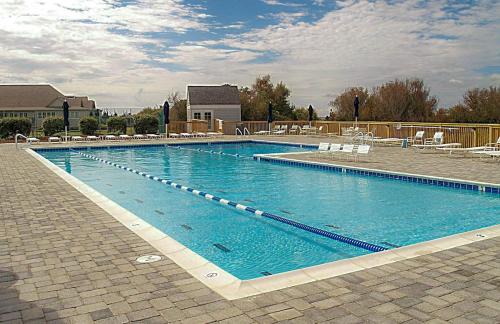 a large swimming pool with blue water and white chairs at Casa La Playa - Duck, Sanderling, Lakefront, 160 Yards to the Beach, Community Pool, Pets OK in Duck