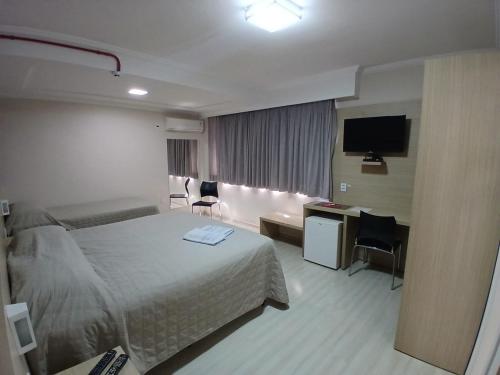 a hotel room with a bed and a desk and a television at HOTEL MARIANI in Lajeado