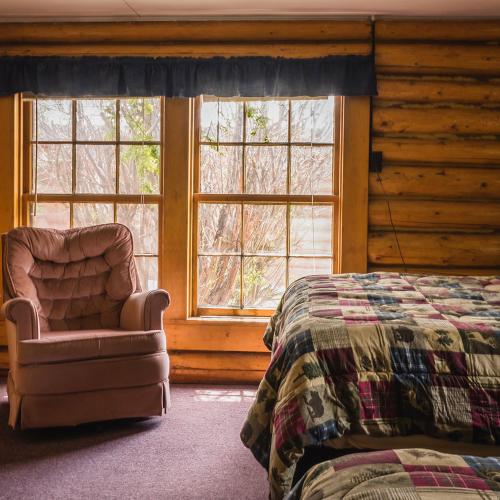 a bedroom with a bed and a chair and windows at Blue Moon Saloon in Cameron