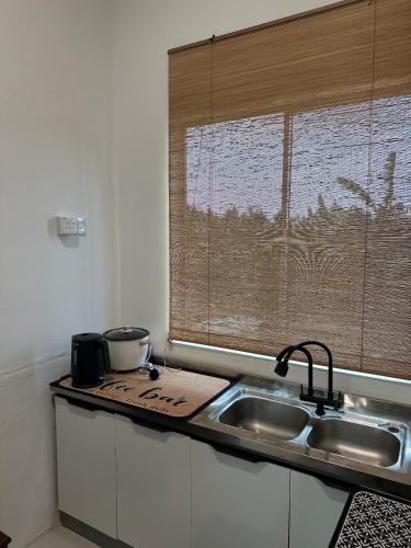 a kitchen counter with a sink and a window at Deyrina Home in Arau