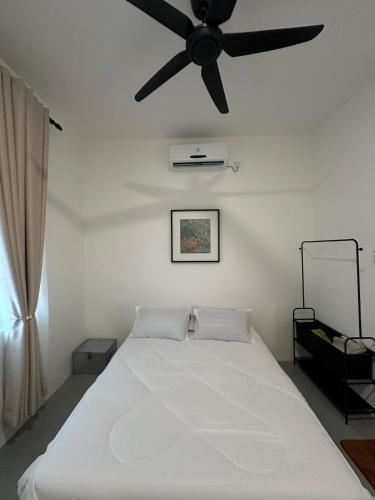a bedroom with a white bed with a ceiling fan at Deyrina Home in Arau