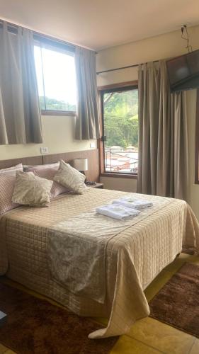 a bedroom with a large bed with a window at Pousada Arco Iris in Gonçalves