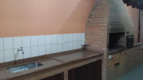 a kitchen with a brick fireplace and a sink at Refugio Massaguaçu in Caraguatatuba
