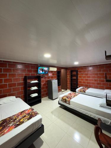 a bedroom with two beds and a tv on a brick wall at ECORAUDAL posada campestre in San José del Guaviare