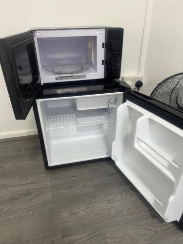 an open refrigerator with a microwave on top of it at Unique Double Bedroom in London