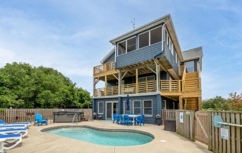 a house with a deck and a swimming pool at Climate Change - Duck, Sea Tern, Oceanside, 280 Yds to Beach, Pool, Hot Tub, Pets OK in Duck