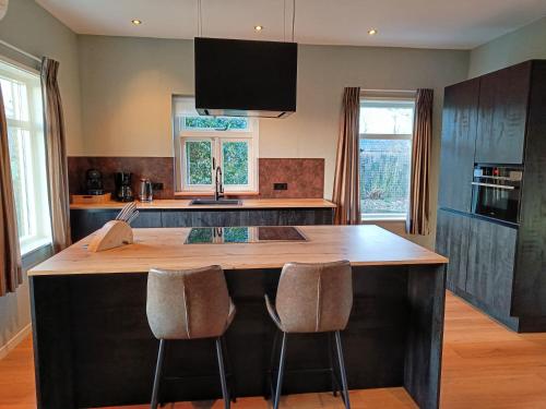 a kitchen with a large wooden island with two bar stools at Vakantiewoning met hottub en bedstede - De Kruidenhoeve in het Reestdal in Balkbrug