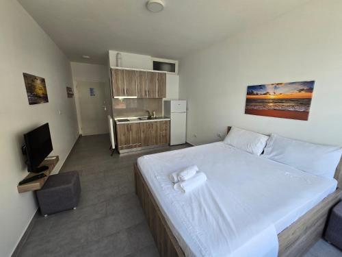 a bedroom with a large white bed and a television at Roxhensi Apartments in Shëngjin