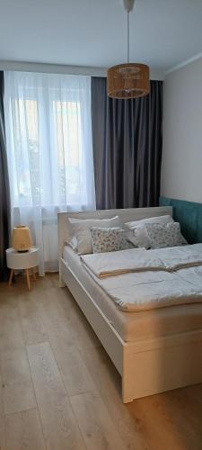 a bedroom with a large bed in front of windows at APARTAMENT RELAX in Ełk