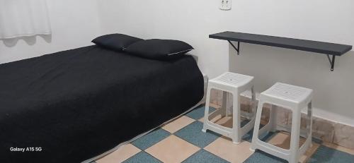 a black bed with a table and two stools at Casa no Centro de Piracicaba - SP in Piracicaba