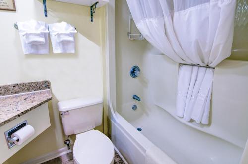 a white bathroom with a toilet and a shower at Palms Resort in Myrtle Beach