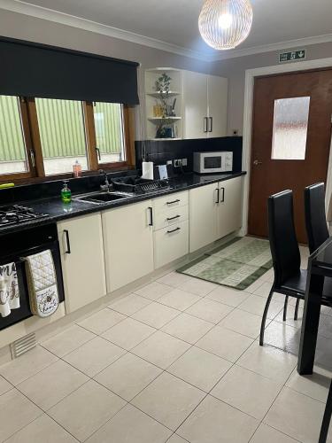 a kitchen with white cabinets and black counter tops at Fraoch, Pets welcome in Port Bannatyne