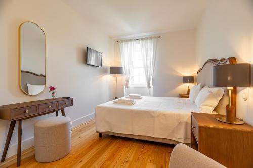 a white bedroom with a bed and a mirror at Boutique Hotel Casa da Brêa Viana do Castelo in Viana do Castelo