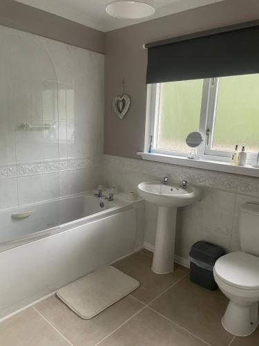 a bathroom with a tub and a toilet and a sink at Fraoch, Pets welcome in Port Bannatyne