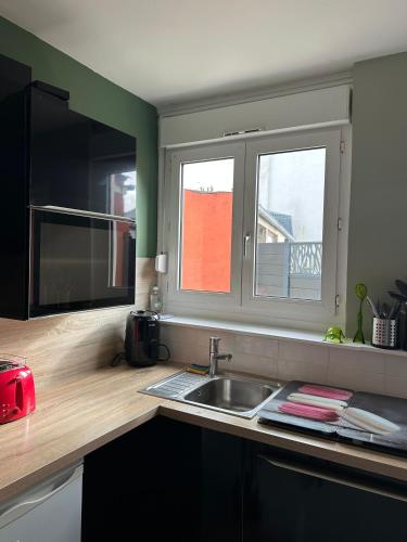 a kitchen with a sink and two windows in it at La Petite Maison in Brest
