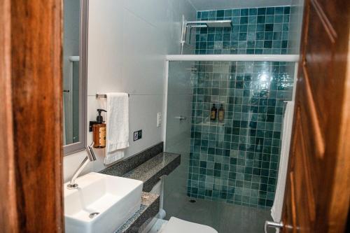 a bathroom with a green tiled shower and a sink at A Flor Pousada in Garanhuns
