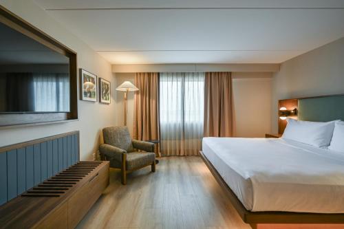 a hotel room with a bed and a chair at Hilton Winnipeg Airport Suites in Winnipeg