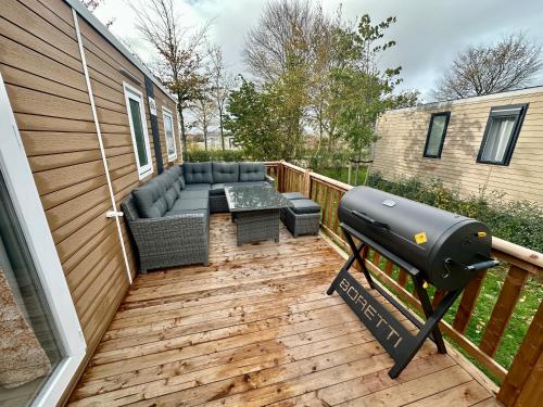 a patio with a bbq and a grill on a deck at Chalet Levy in Lauwersoog